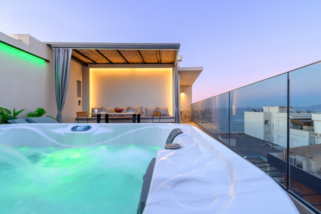 Relaxing private jacuzzi with glowing mood lights, steps away from the elegant balcony dining lounge and stunning sunset views at ELEANA Beach Suites.