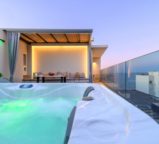 Relaxing private jacuzzi with glowing mood lights, steps away from the elegant balcony dining lounge and stunning sunset views at ELEANA Beach Suites.