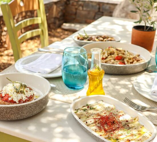Traditional Cretan dishes served on an outdoor table, including dakos, seafood appetizers, and fresh salads.