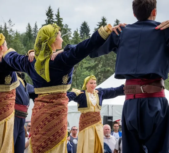 Cretan dancers in traditional costumes performing a circle dance during a cultural event.